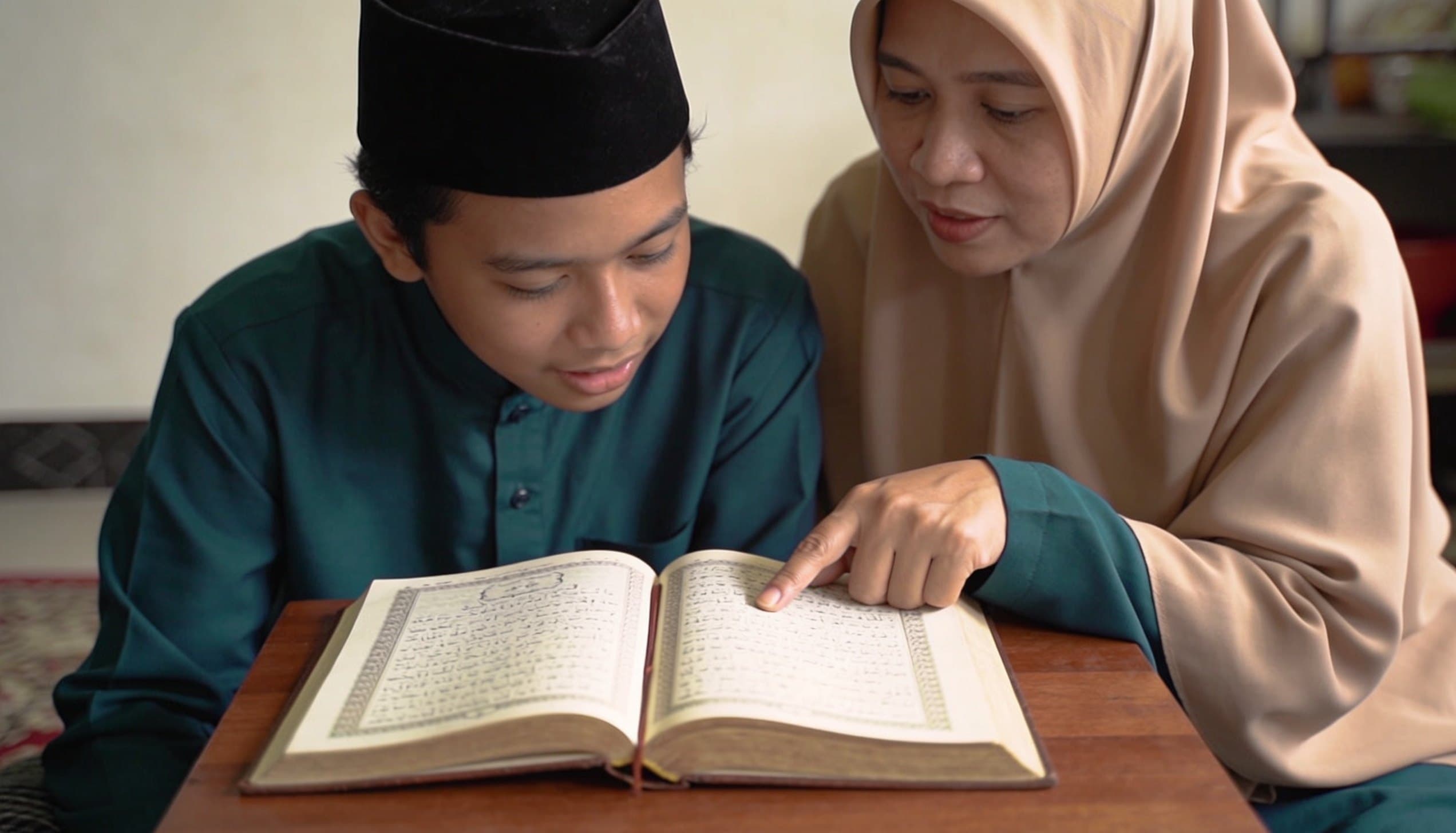 Halaman mushaf yang terbuka dengan pensil dan buku catatan di sampingnya